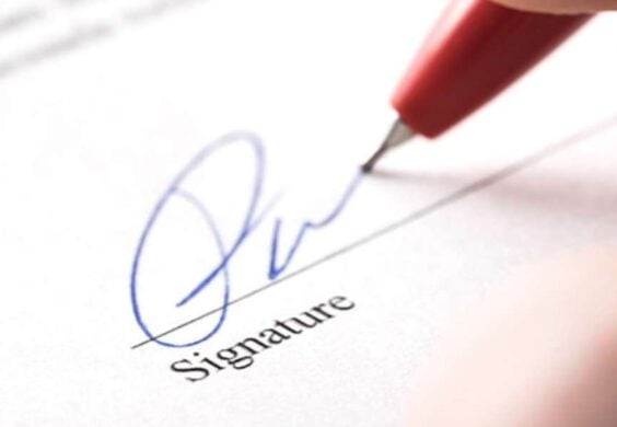 person signing their name on document