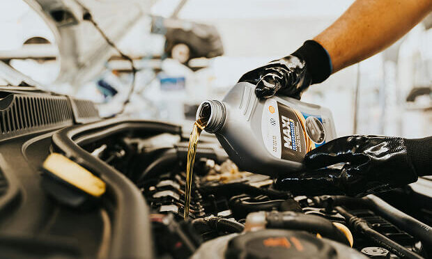 man pouring oil into car