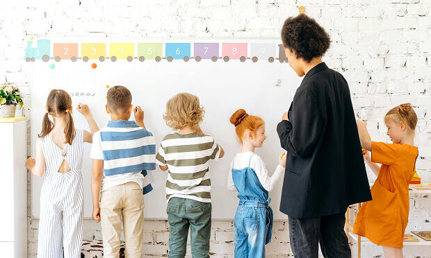elementary teacher interacting with students drawing on white board