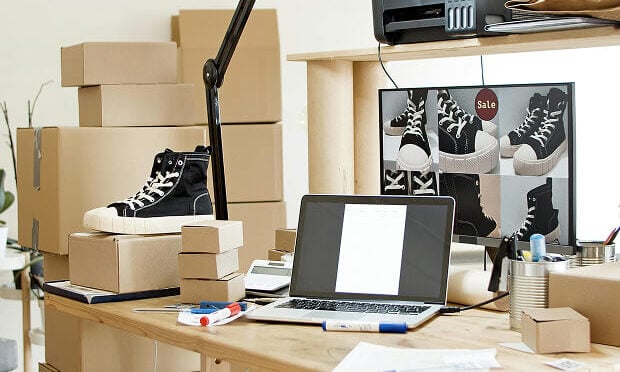 cardboard boxes stacked near desk with laptop and printer