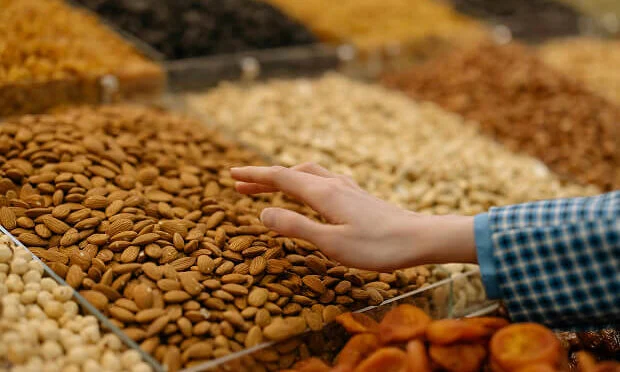 person grabbing a handful of almonds inside nuts store