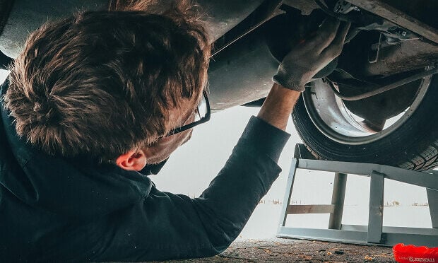 man inspecting underneath a vehicle
