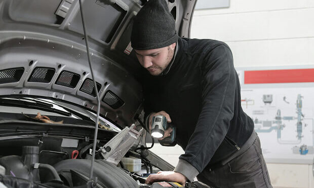 man inspecting underneath the hood of a car