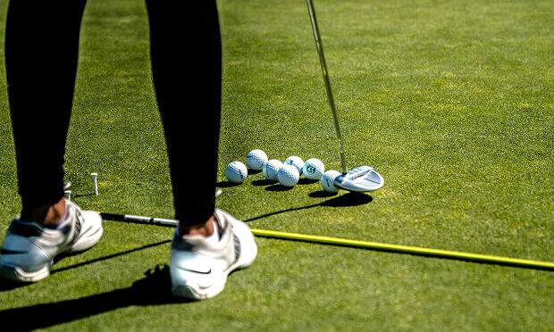 woman lining up golf balls with club