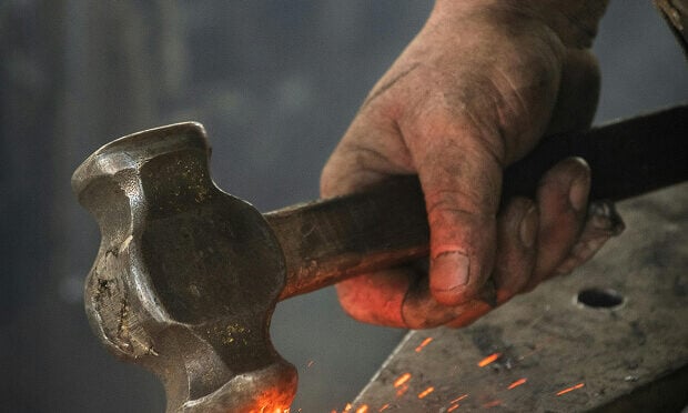 man hammering onto burning iron