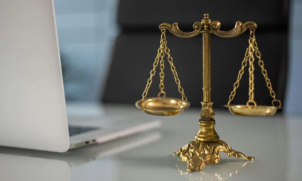 Scale of Justice sitting on desk next to laptop