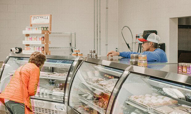 woman looking at meat containers inside of deli
