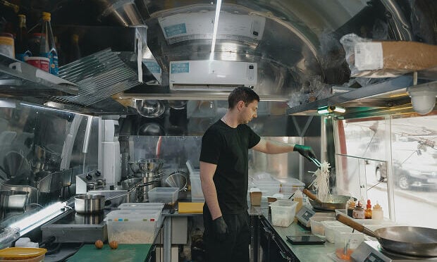 man cooking noodles inside of food truck