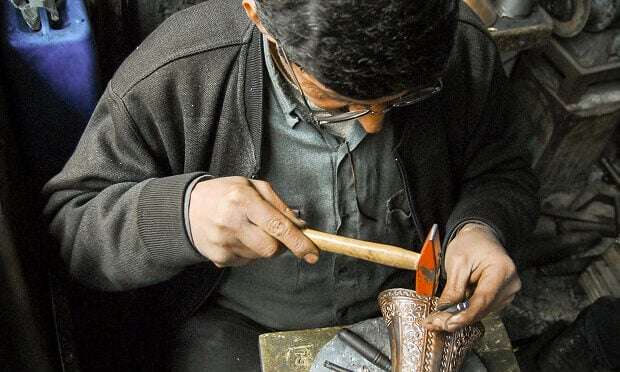 man fixing metal piece with hammer