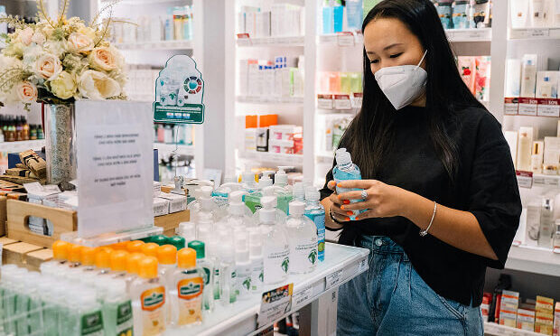 woman holding bottle of hand sanitizer inside a pharmacy