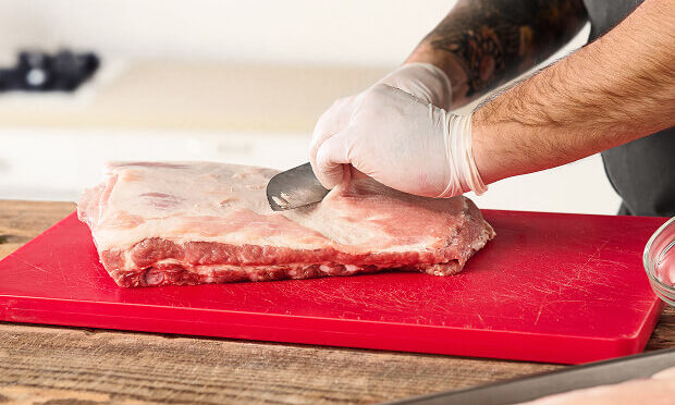man slicing slab of meat