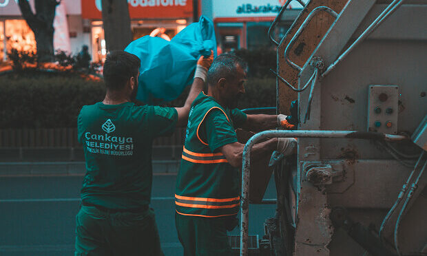 garbage men putting waste in garbage truck