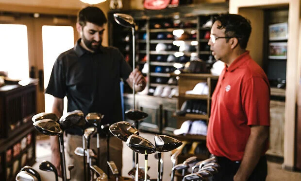 man and sales clerk looking at golf club